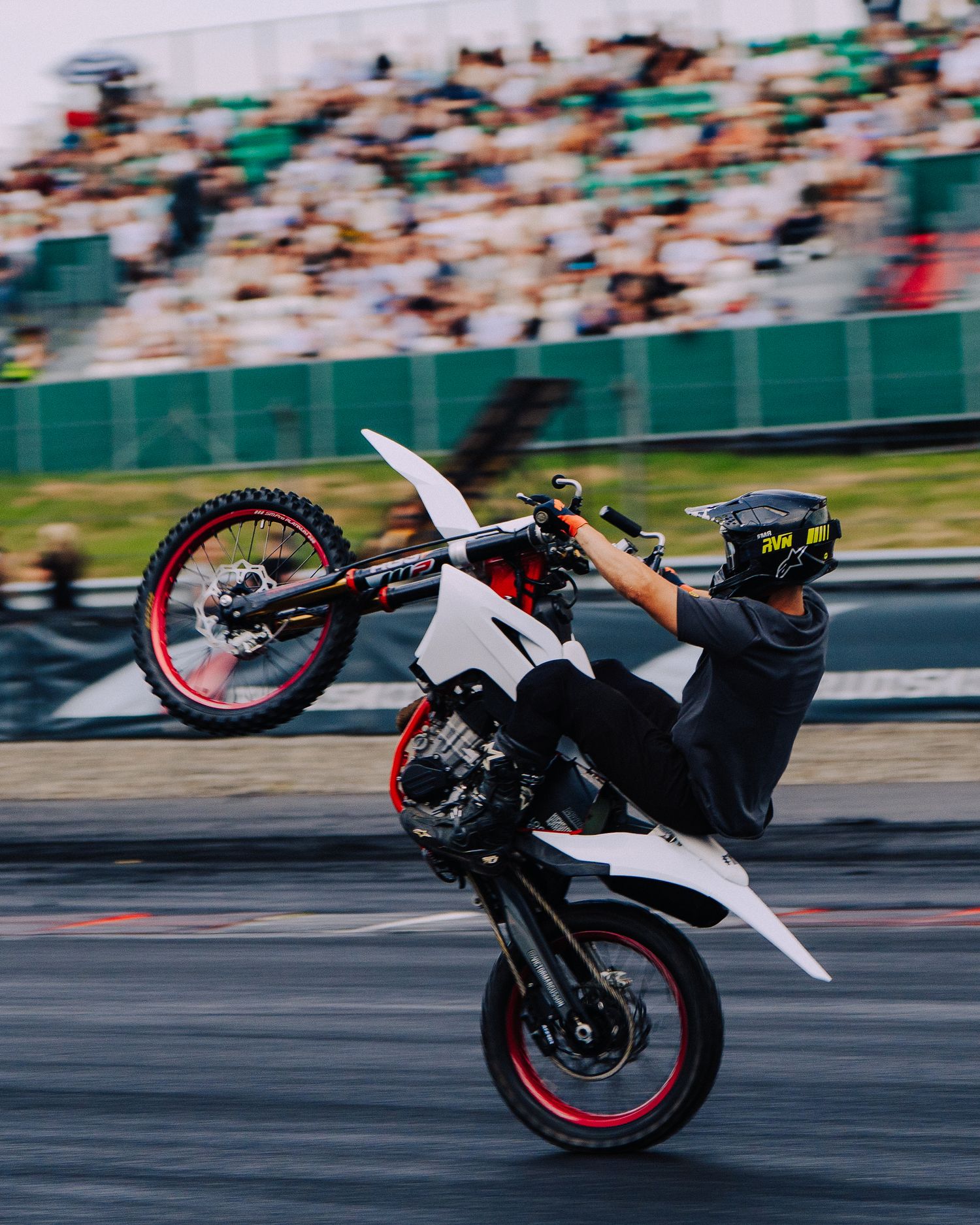 A motorcycle rider performs a wheelie stunt sequence on a racetrack, showing progression from start to vertical position.