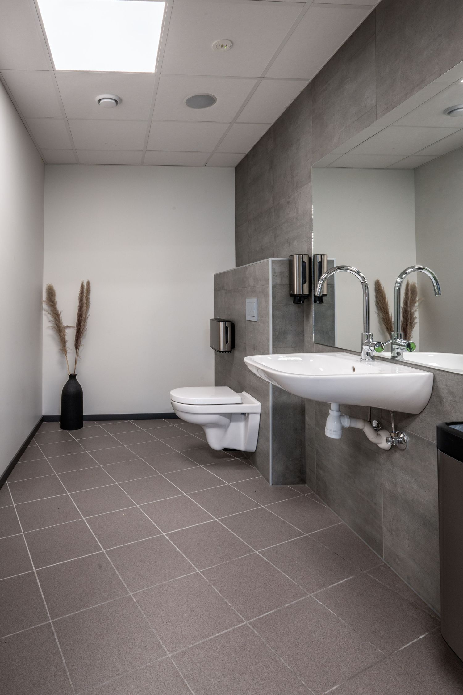 Minimalist bathroom with gray tile floors, white walls, and modern fixtures.