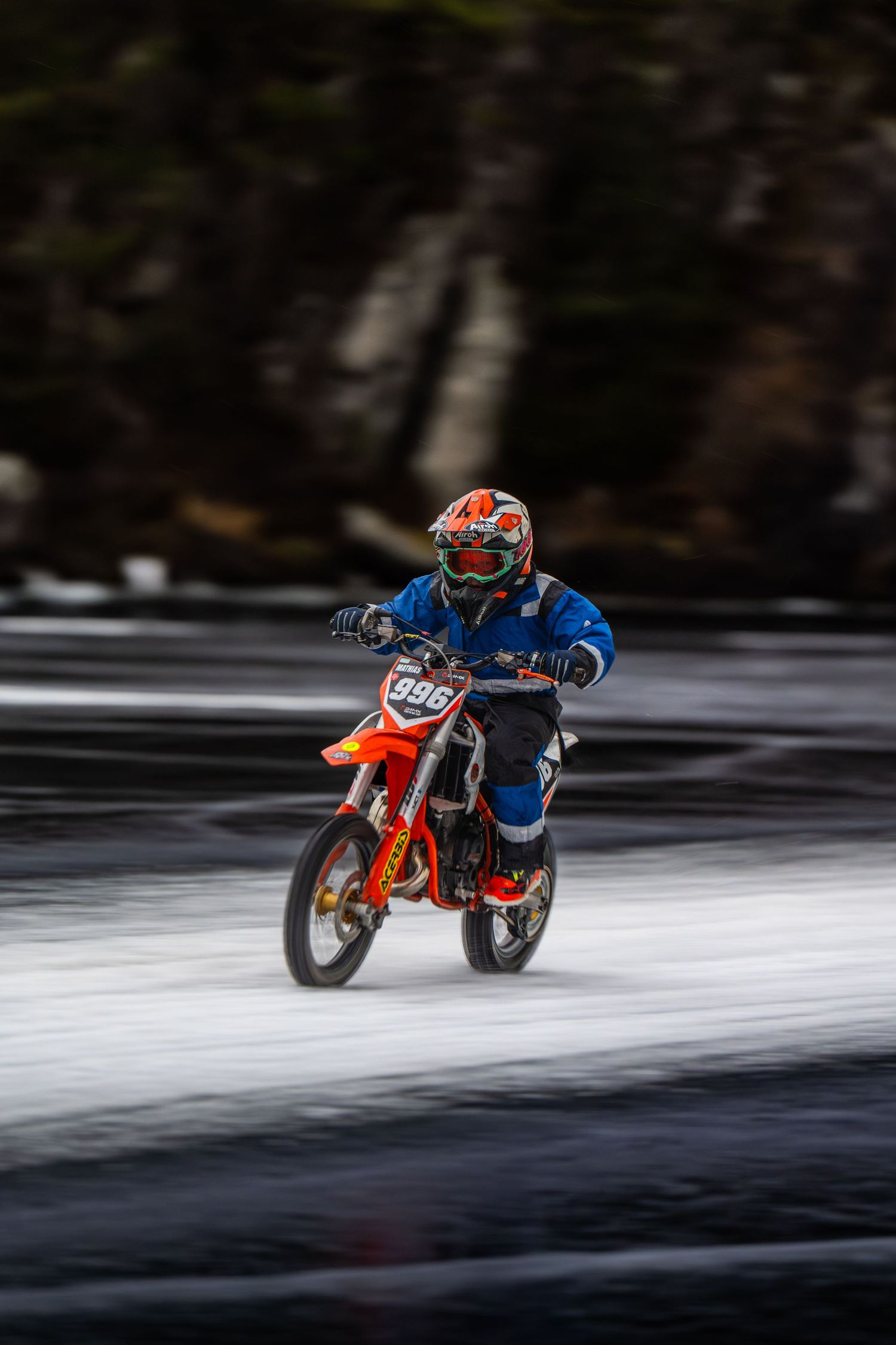 Motorcyclist racing on a frozen lake surface with motion blur effect creating a dramatic winter sports scene.