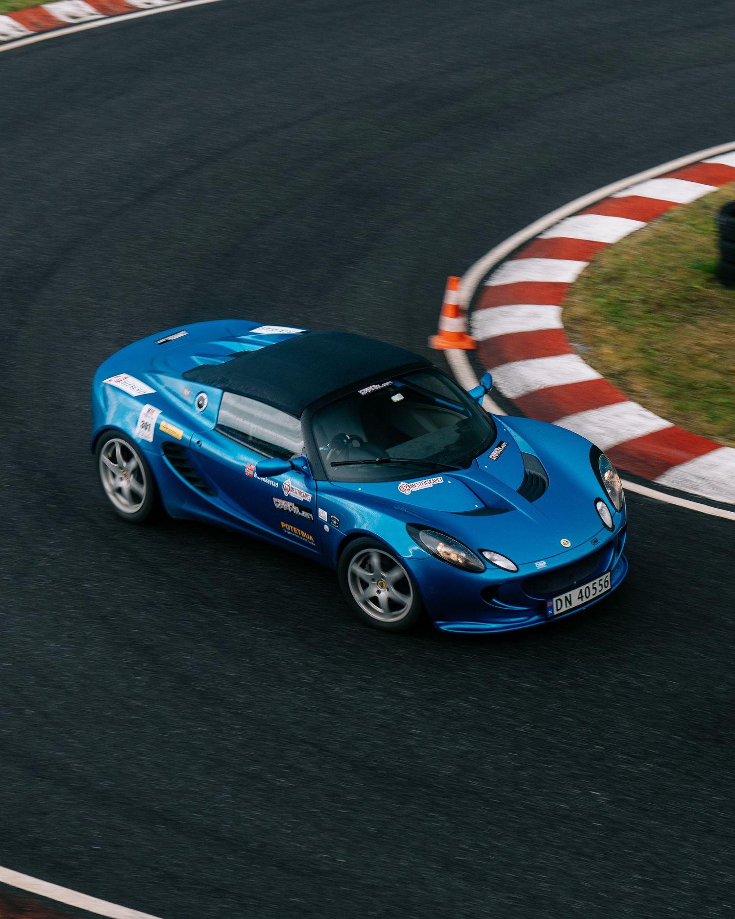 A blue Ferrari LaFerrari supercar races around a racetrack with red and white curbing.