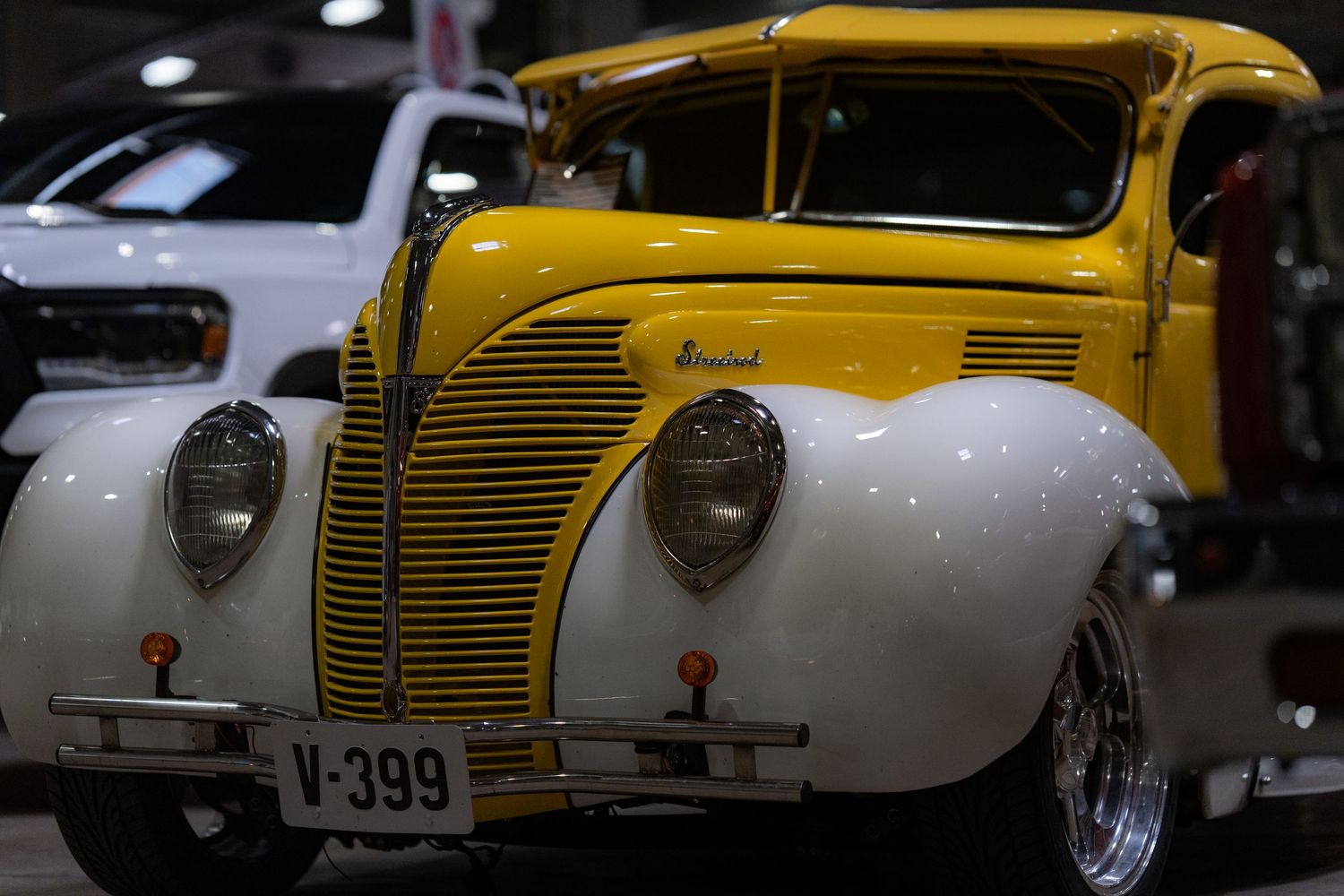 Yellow and white 1939 classic car front end with chrome grille at car show.