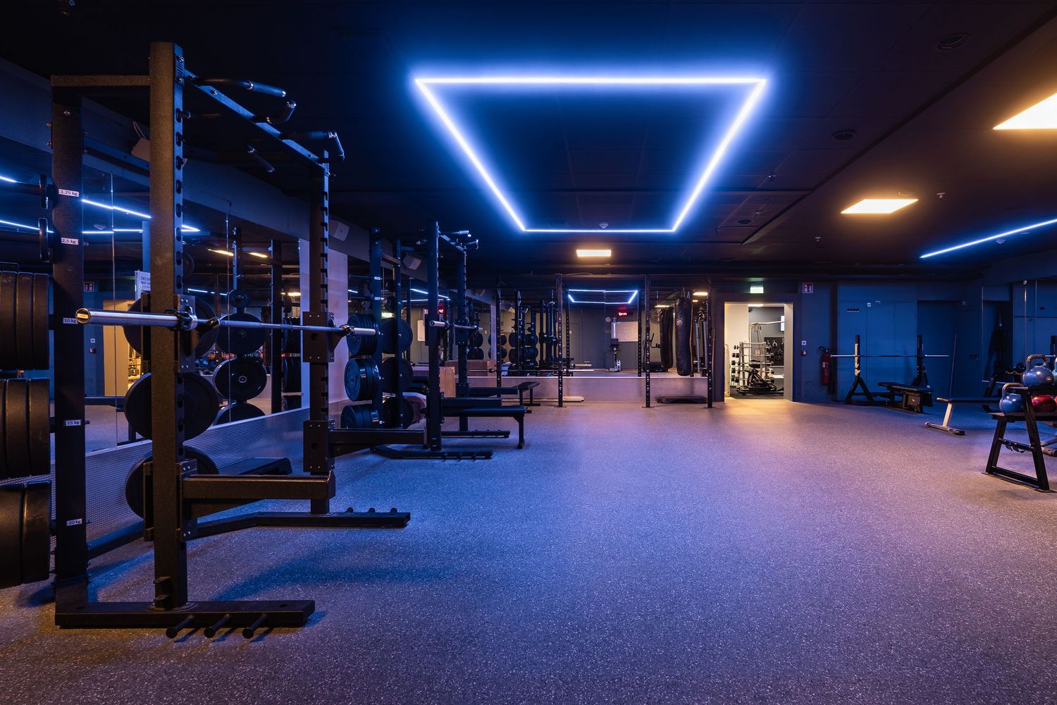 Modern gym space with triangular blue LED ceiling lights and weight training equipment.