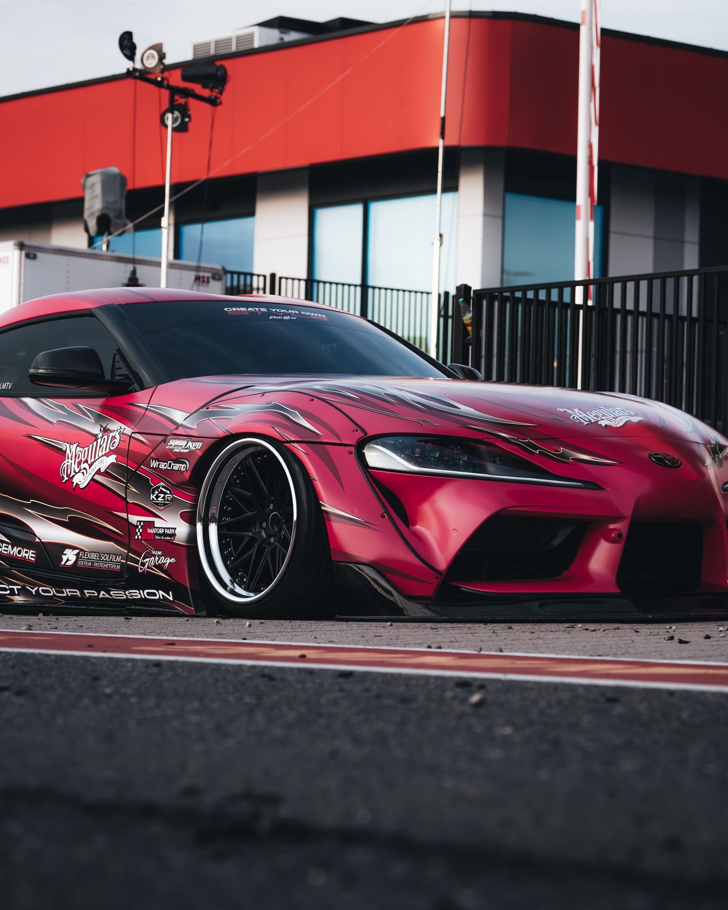 A sleek red sports car with custom wide body kit and low profile stance shown from multiple angles on a dark surface.
