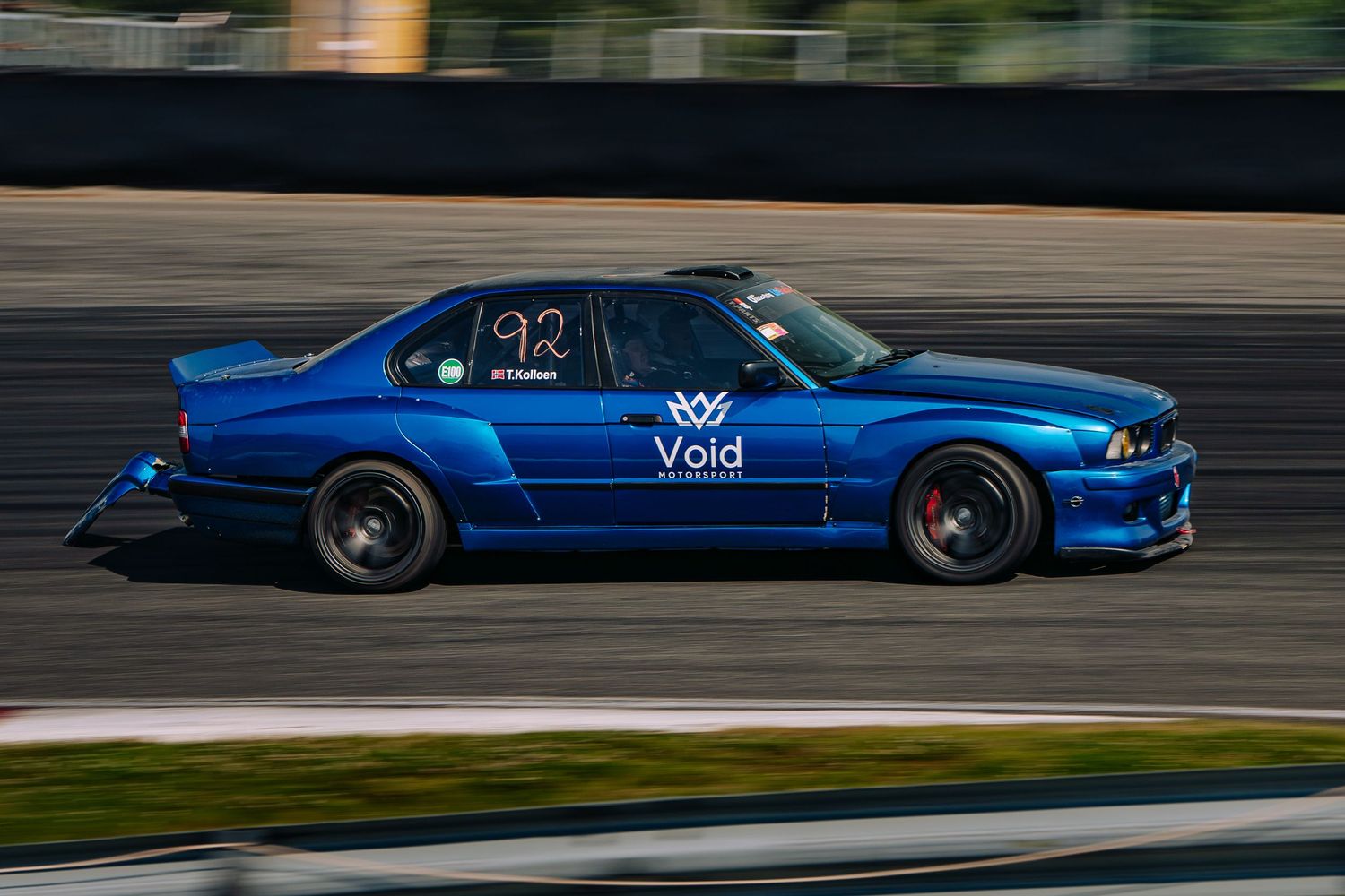 A blue modified Nissan Skyline GTR sports car with black wheels performs on a racetrack.