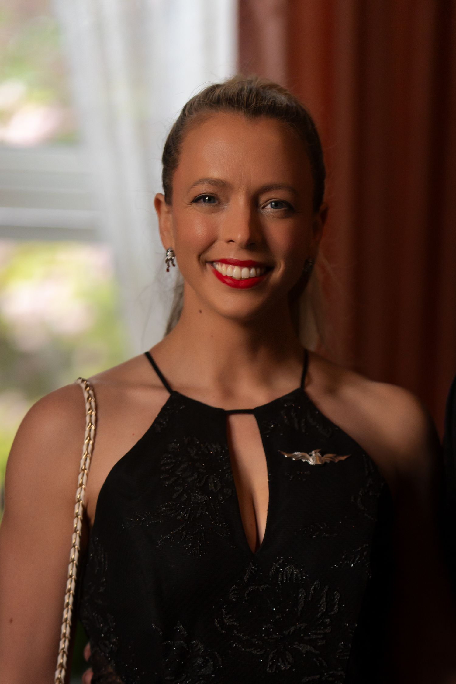 Elegant partygoer in black sleeveless dress with statement red lipstick at formal event.