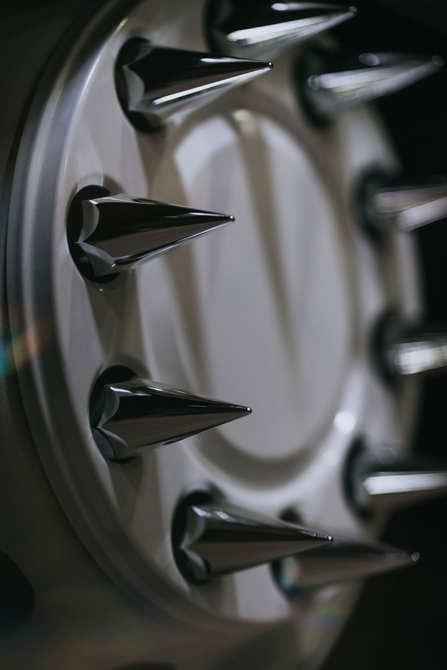 Macro shot of metallic spikes on custom wheel hub in dramatic lighting.