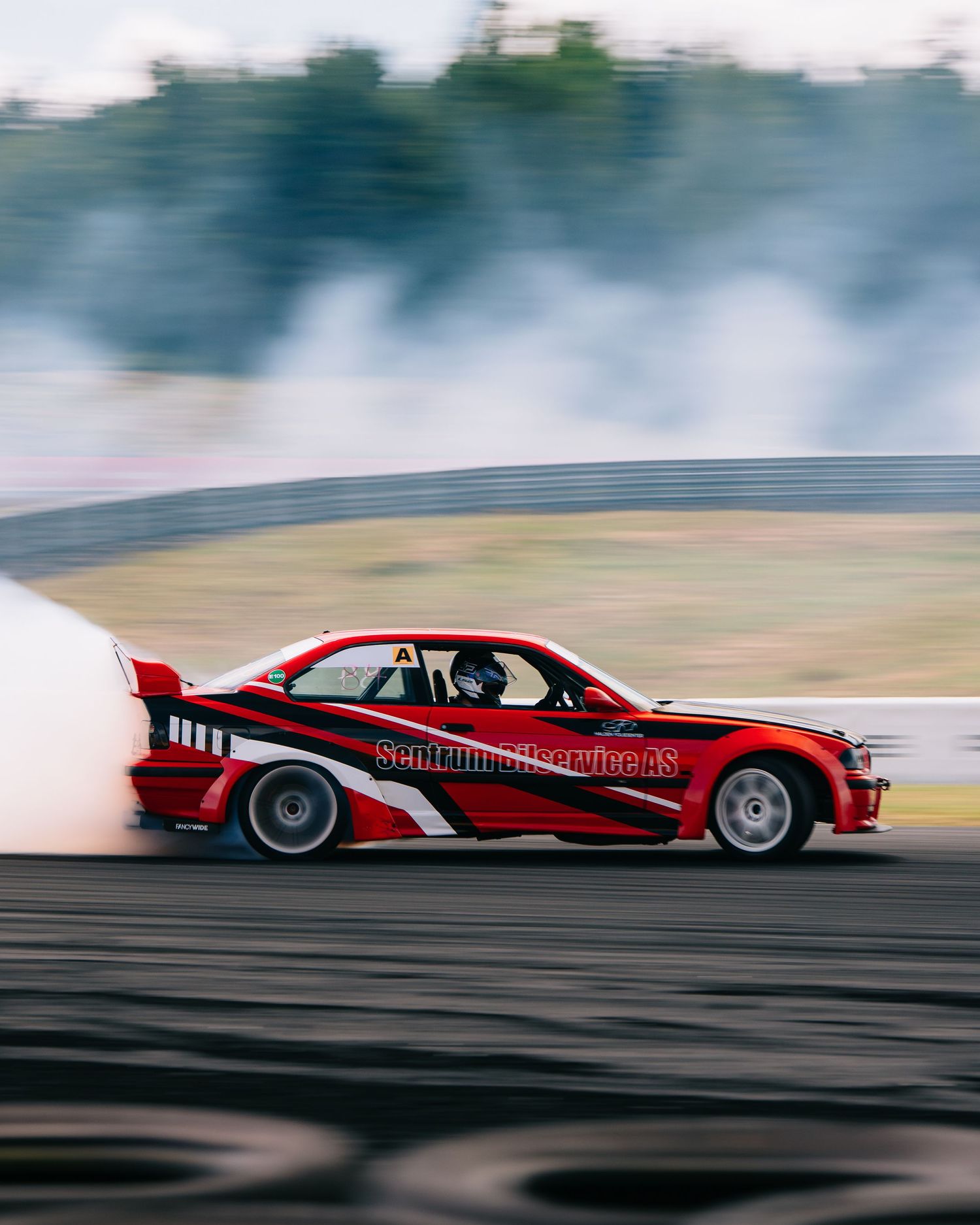 Red racing car drifting on track with motion blur creating a dynamic action shot.