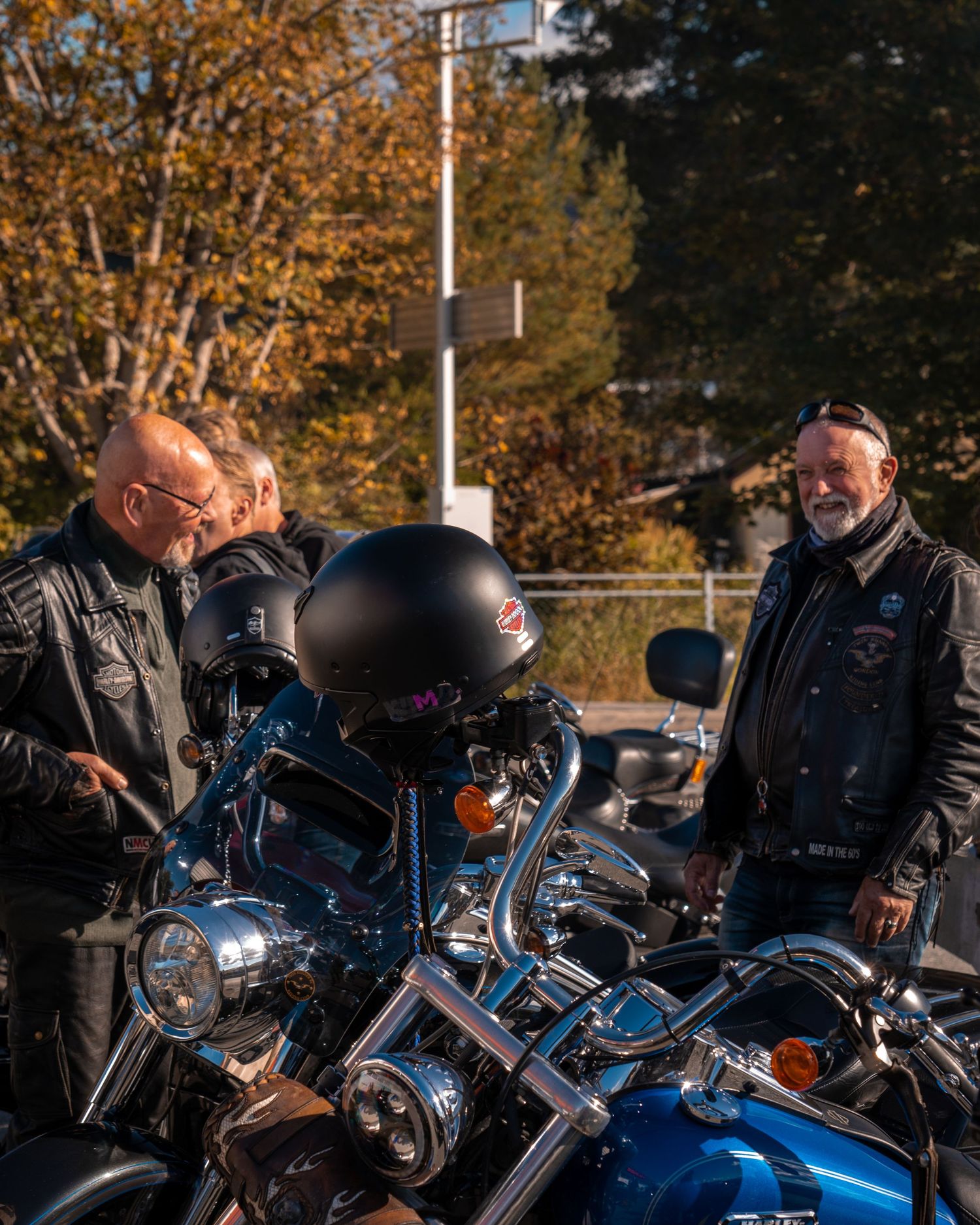 Two motorcycle enthusiasts examining and discussing bikes in an outdoor setting.