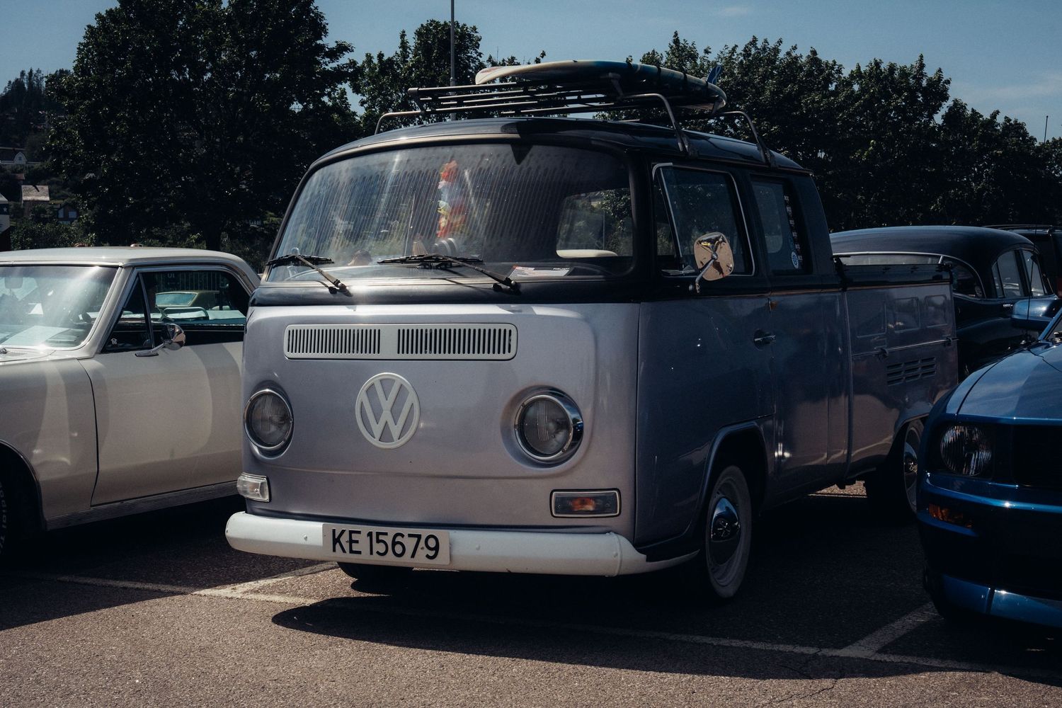 Classic Volkswagen vehicles arranged in a row at a vintage car meetup.