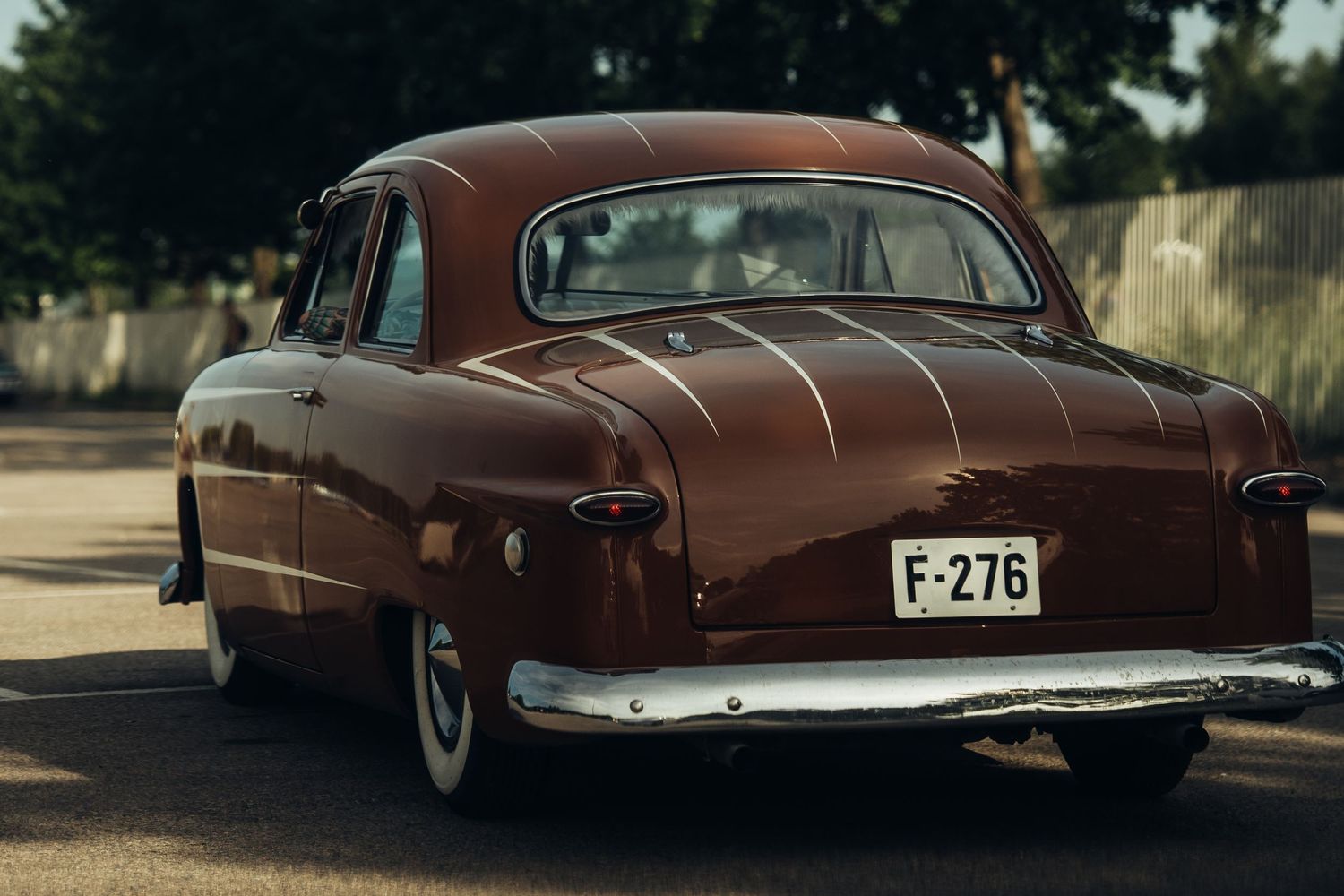 Rear view of a brown classic 1950s sedan with curved body lines.