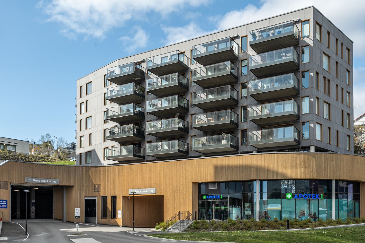 Multi-story apartment building with wooden accents and glass balconies in an urban setting.