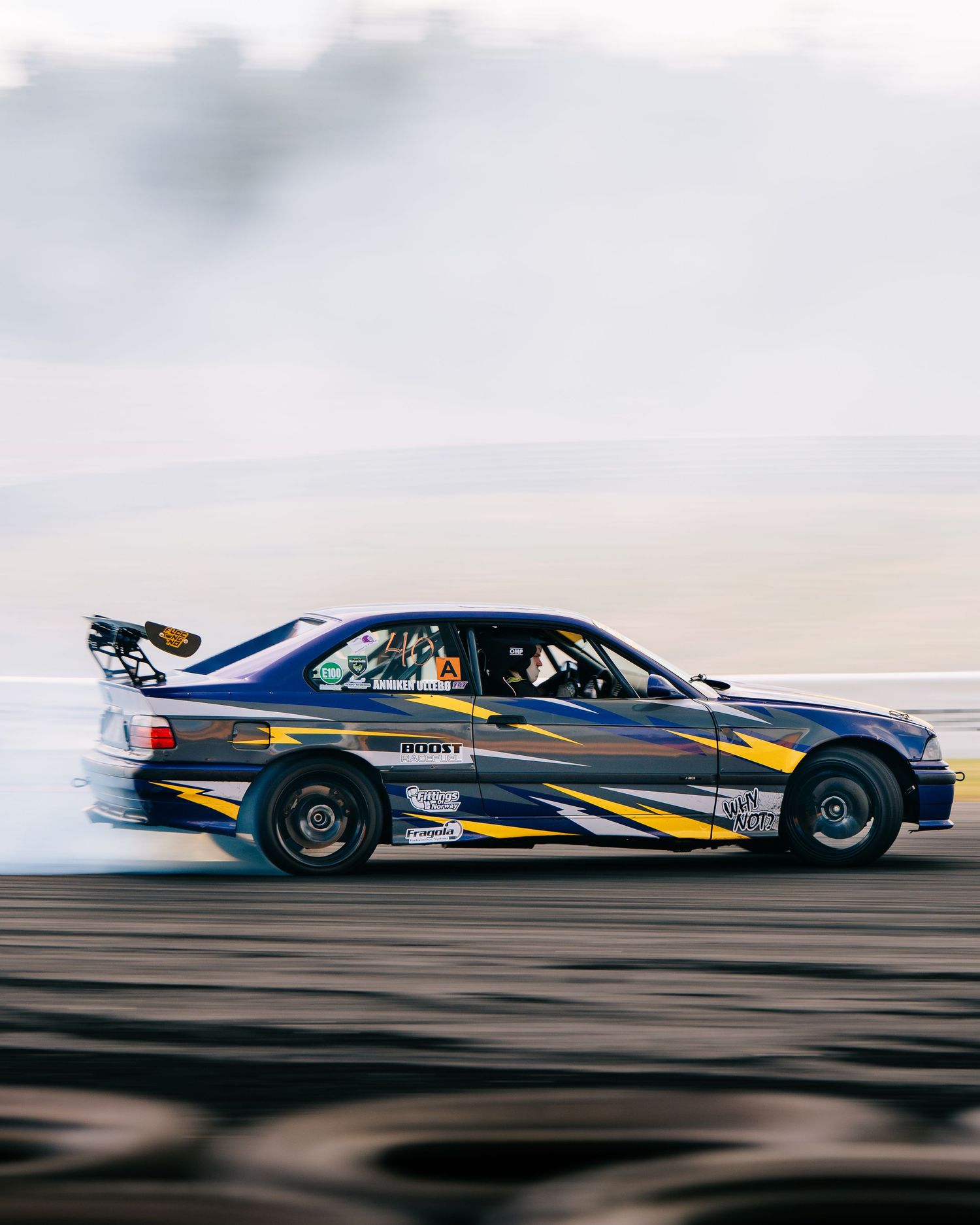 A sequence of four motion-blurred drag racing cars speeding down a racetrack at high velocity.