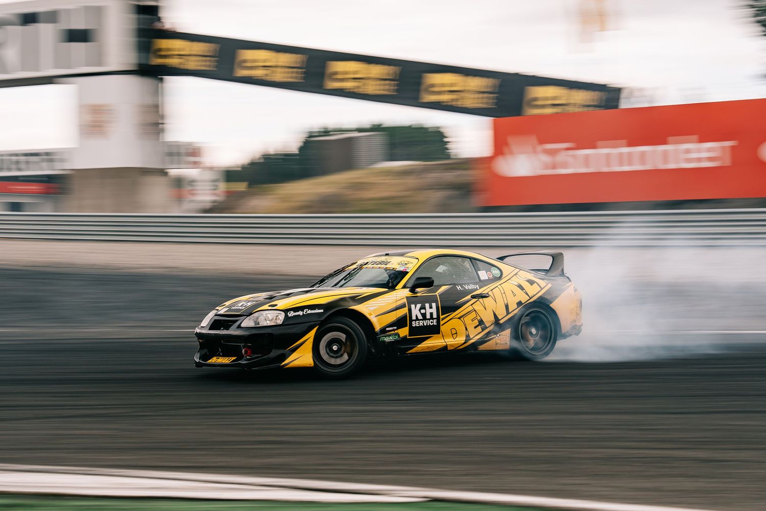 Race car speeds past in a blur of motion on a professional racing track, showing dynamic movement and speed.