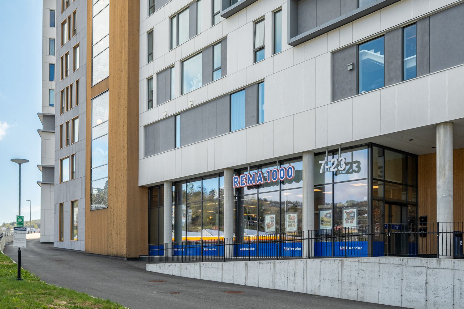 Street-level view of modern apartment complex with commercial spaces and geometric architecture.