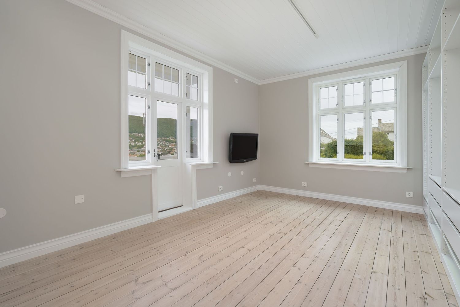 Spacious minimalist living area with white trim and light-colored hardwood floors throughout.