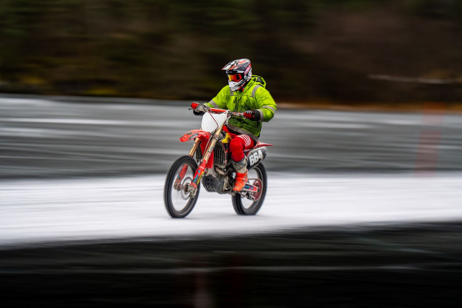 A sequence of motion-blurred photos showing a red dirt bike rider performing jumps on a race track.