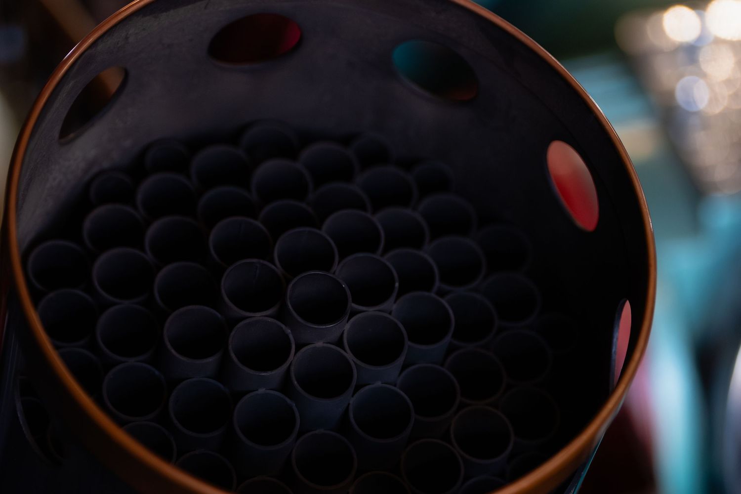 Close-up view of black drinking straws arranged in a circular pattern inside a dark container with red accents.