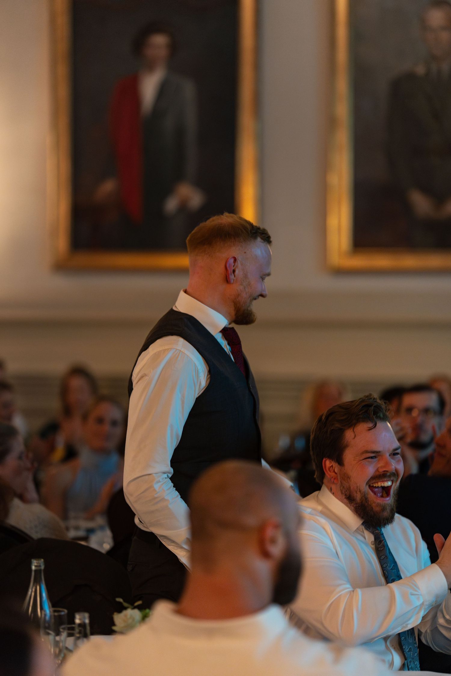Candid moment of guests laughing and enjoying themselves during a formal indoor celebration.
