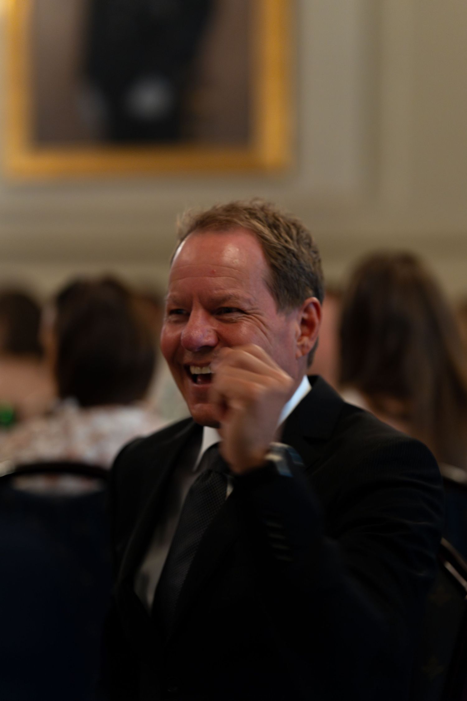 Event attendees enjoying humorous conversation in formal attire.