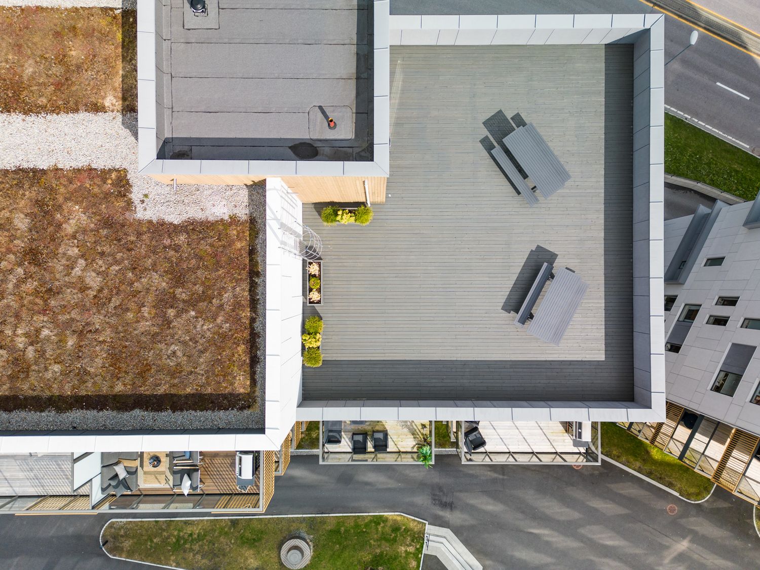 Aerial view of modern white building rooftops with outdoor terraces and balconies.
