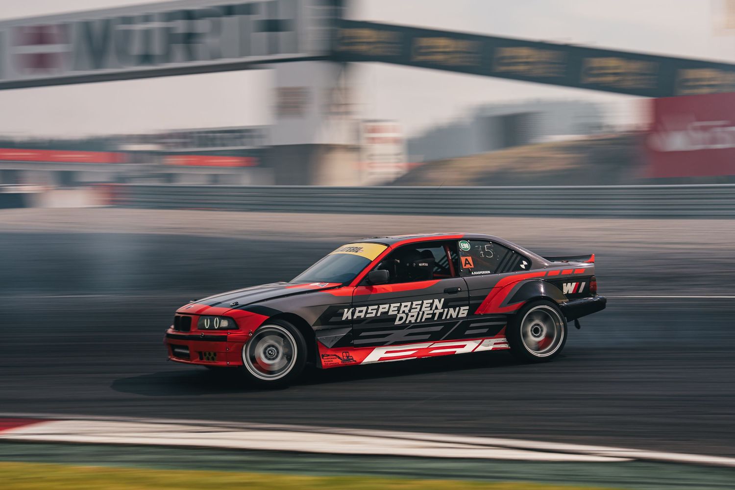 A sequence of motion-blurred shots showing a red and black drift car performing at high speeds on a racetrack.