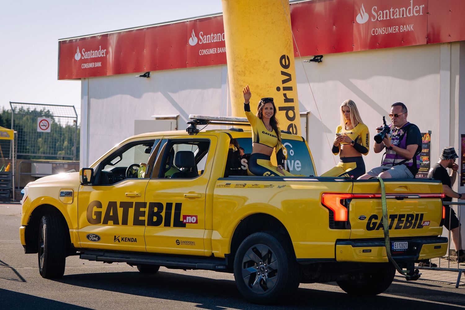 Yellow Caterpillar equipment service trucks lined up in a row outside a Santander bank building.