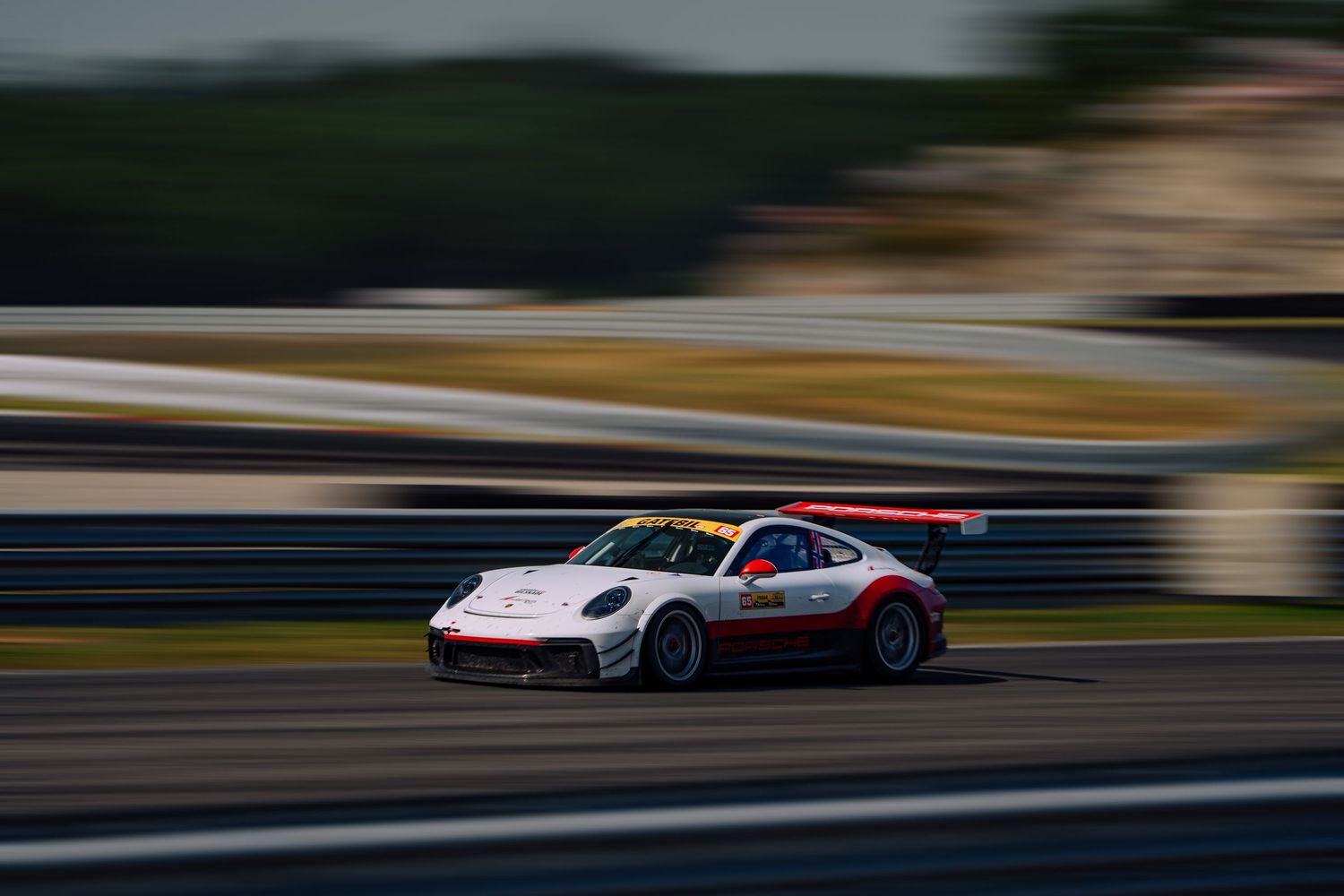 Racing car speeds along racetrack with motion blur creating dynamic sense of movement and speed.