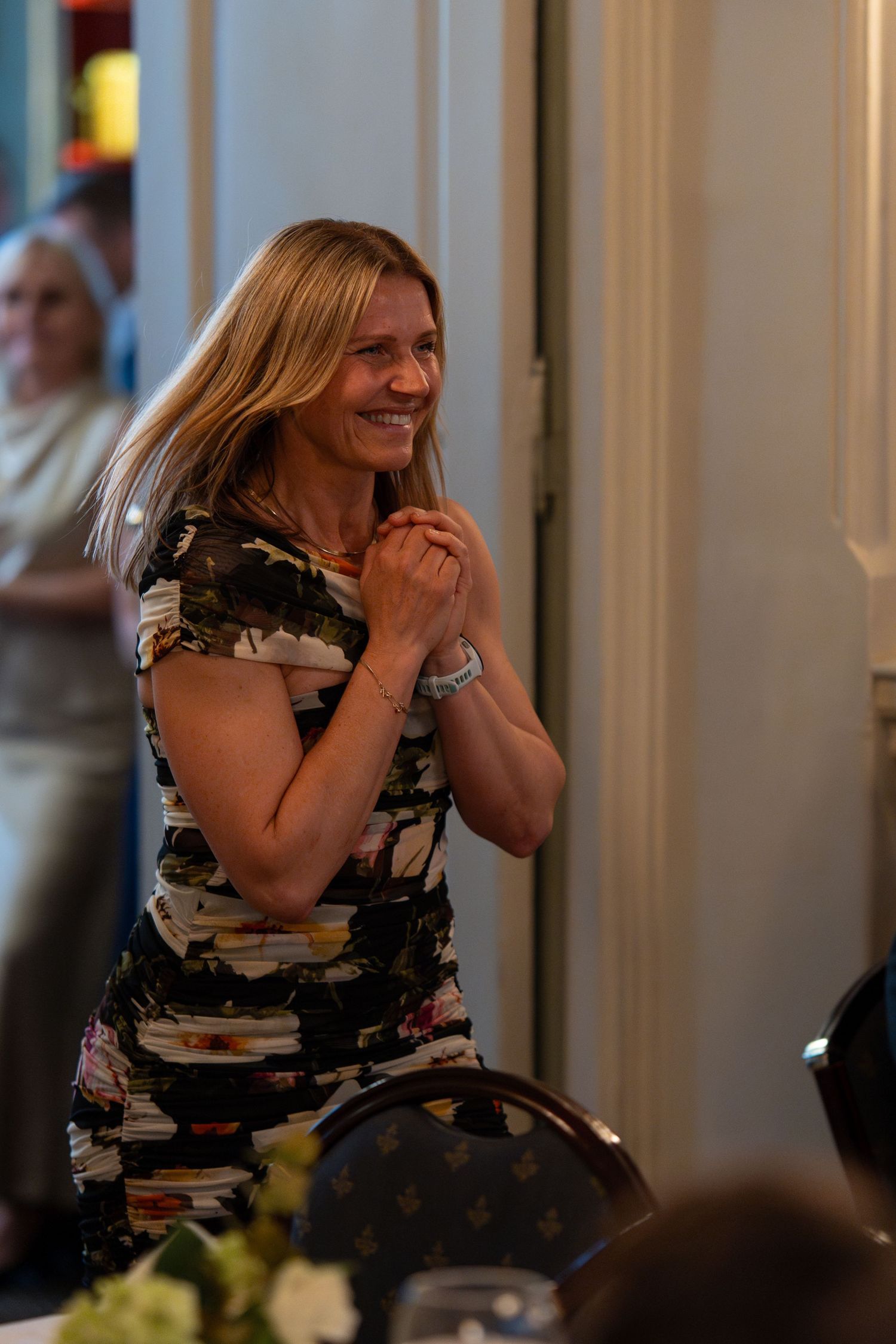 Guest in floral dress reacts with excitement during formal dinner event.