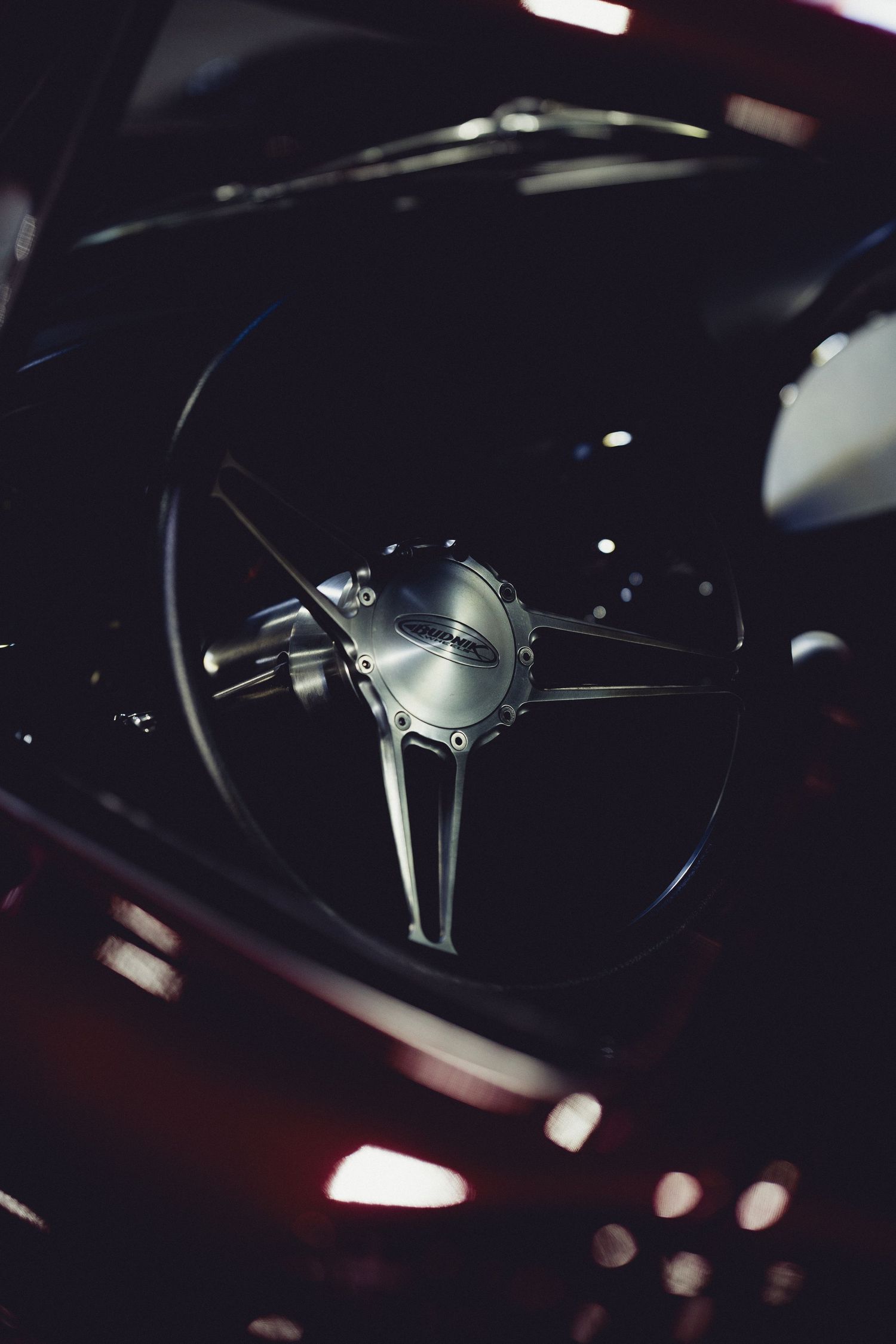 Close-up shot of a modern car's steering wheel in dark lighting with ambient illumination.