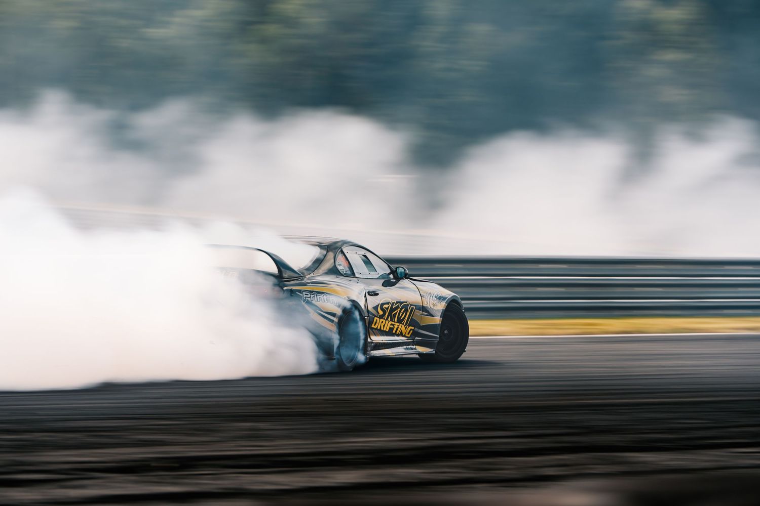 Race car drifts through smoke on a racetrack with dramatic motion blur effect.