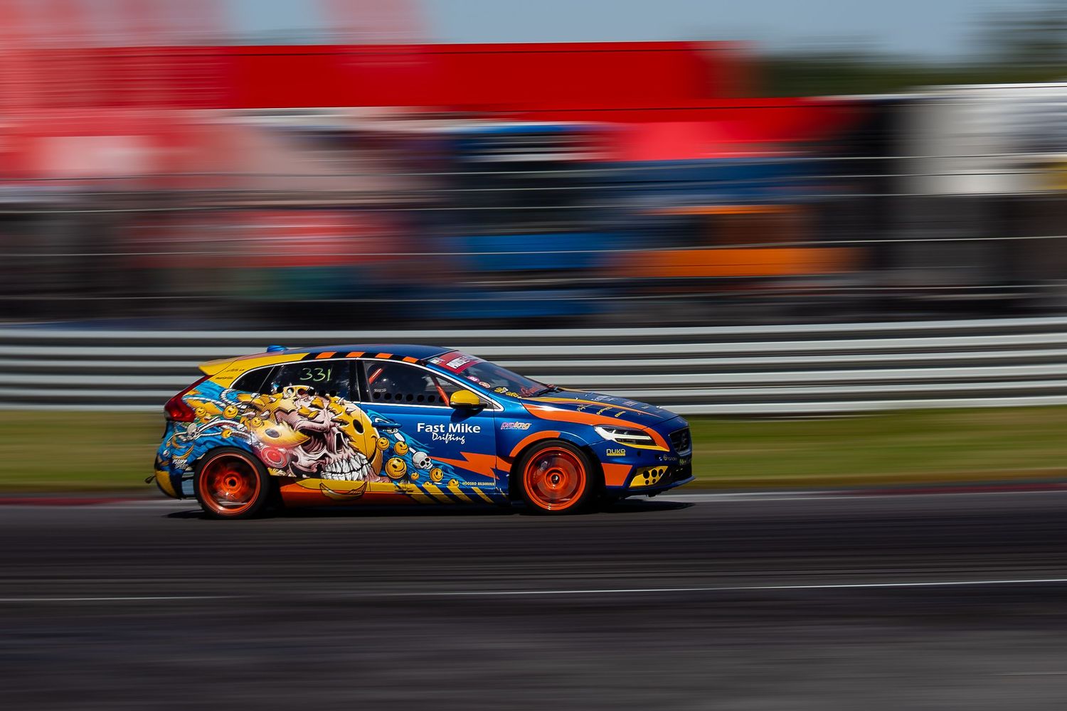 A colorfully decorated race car speeds along a racetrack with motion blur in the background.