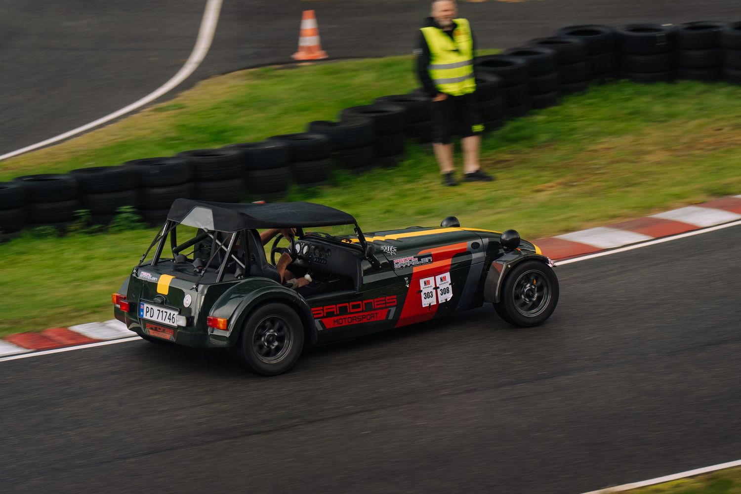 Racing cars navigate a wet racetrack during a motorsport competition in rainy conditions.