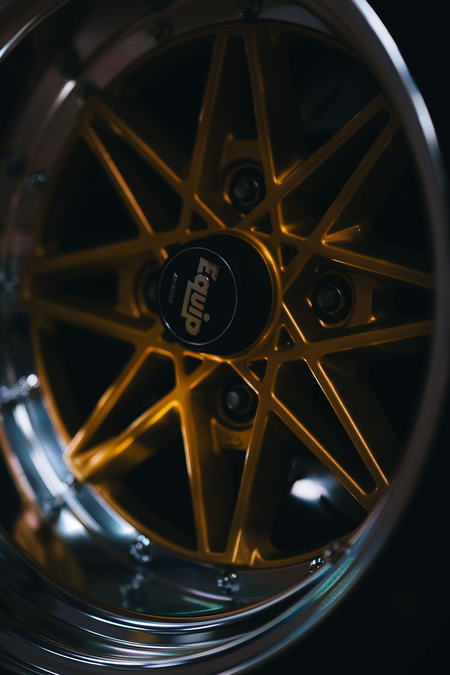 Custom gold-colored alloy wheel with intricate spoke design in low light.