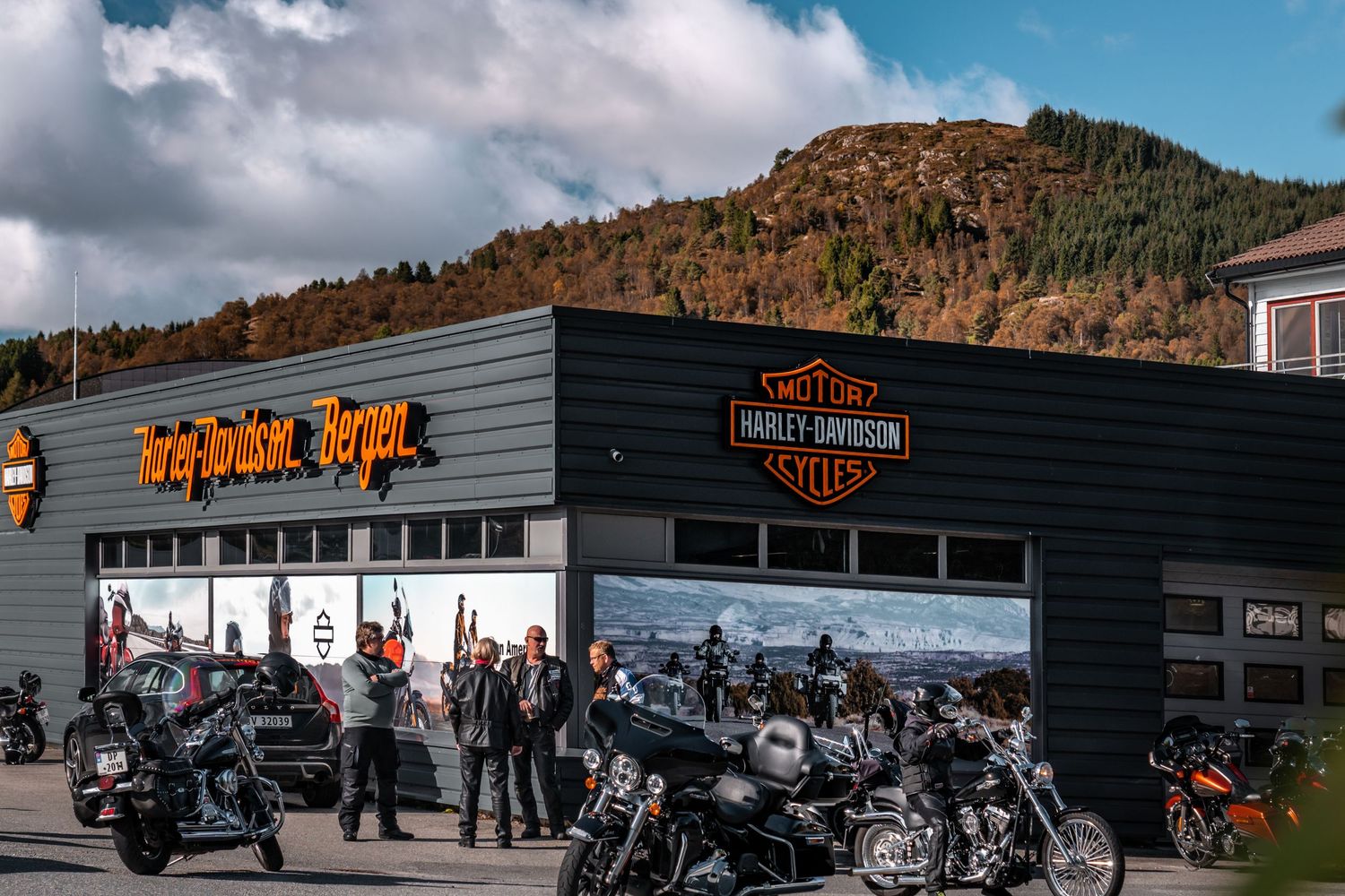 Panoramic view of Harley-Davidson dealership with mountains and blue sky in background.