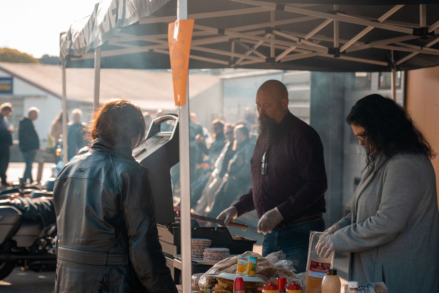 People gathered around a food station at an outdoor motorcycle event.