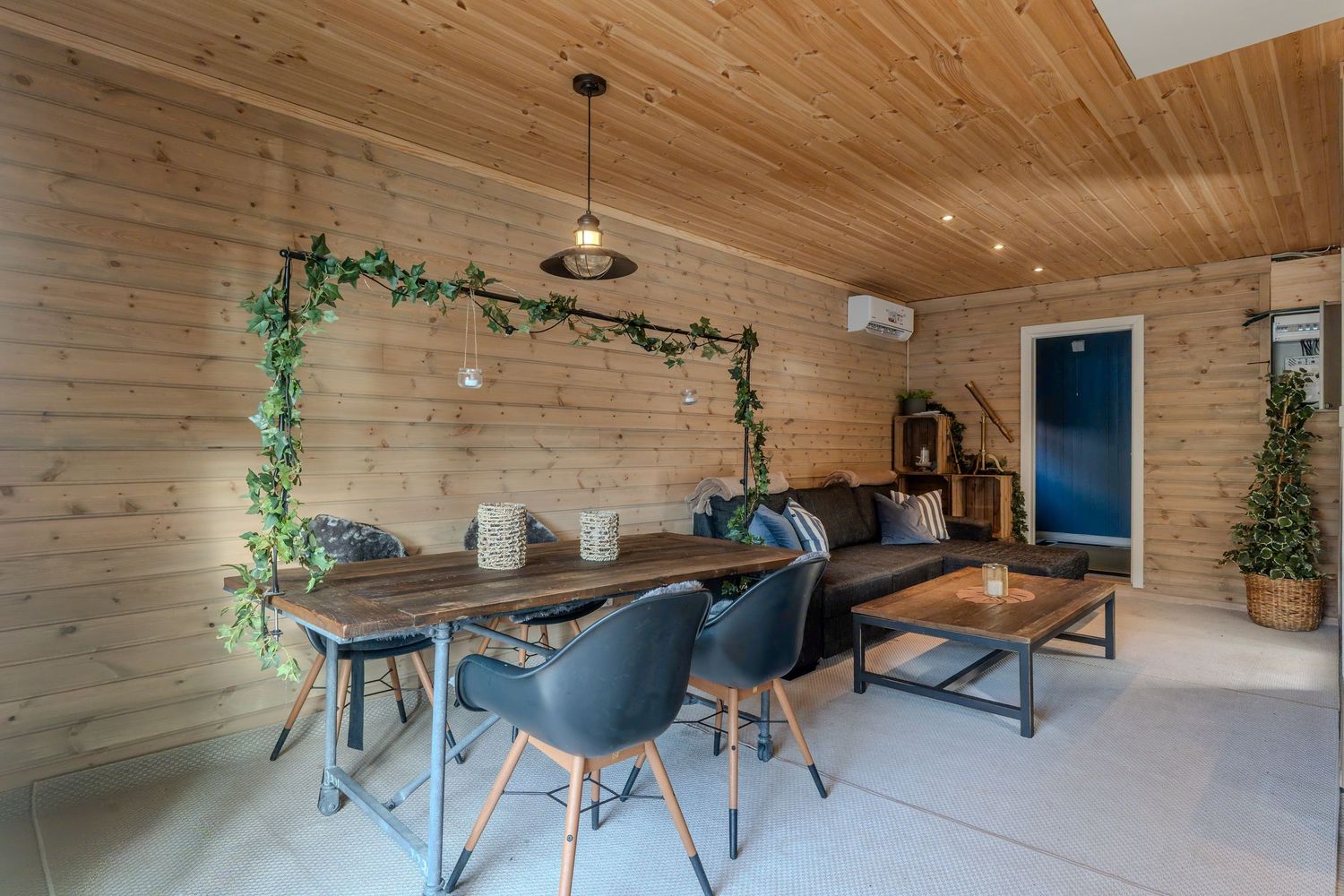 Rustic dining area with wood paneled walls, blue chairs, and decorative vine accents.