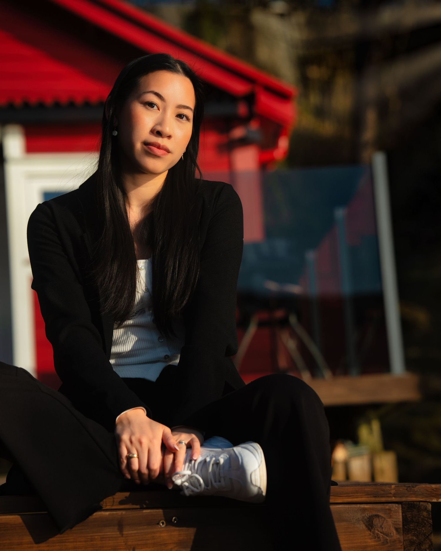 Woman in athletic wear sitting outdoors with red building in background.