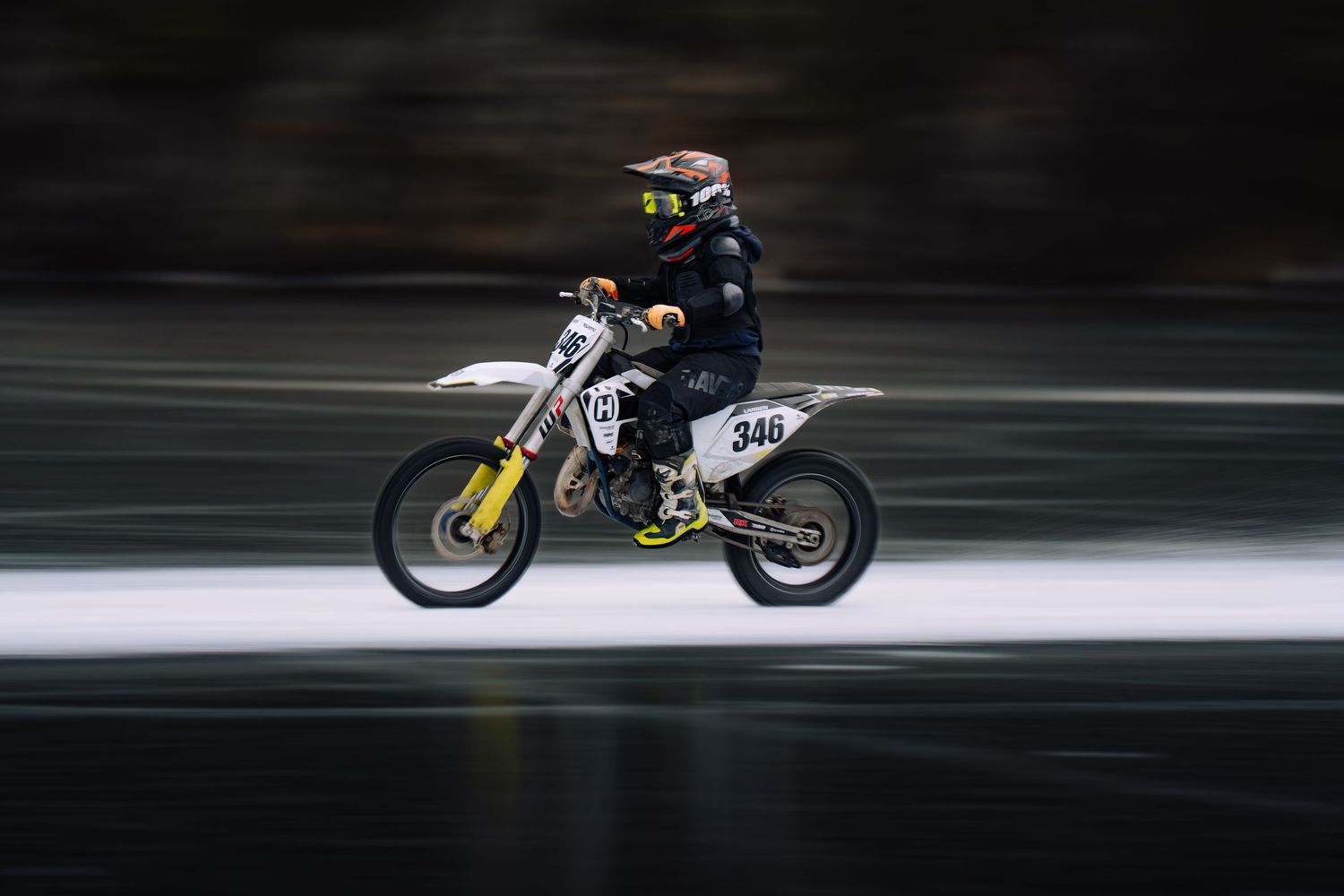 Racing motorcycle in motion creates dramatic speed blur effect on dark track.
