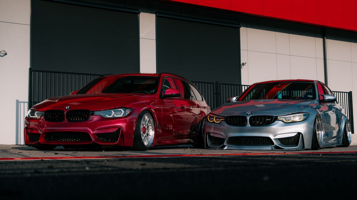 Sleek luxury cars on display in a modern car dealership showroom with red and black interior design elements.