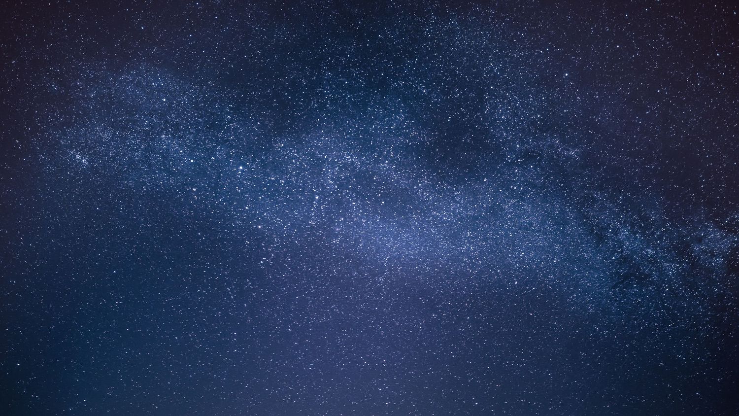 Dark blue night sky filled with bright stars and the glowing band of the Milky Way.