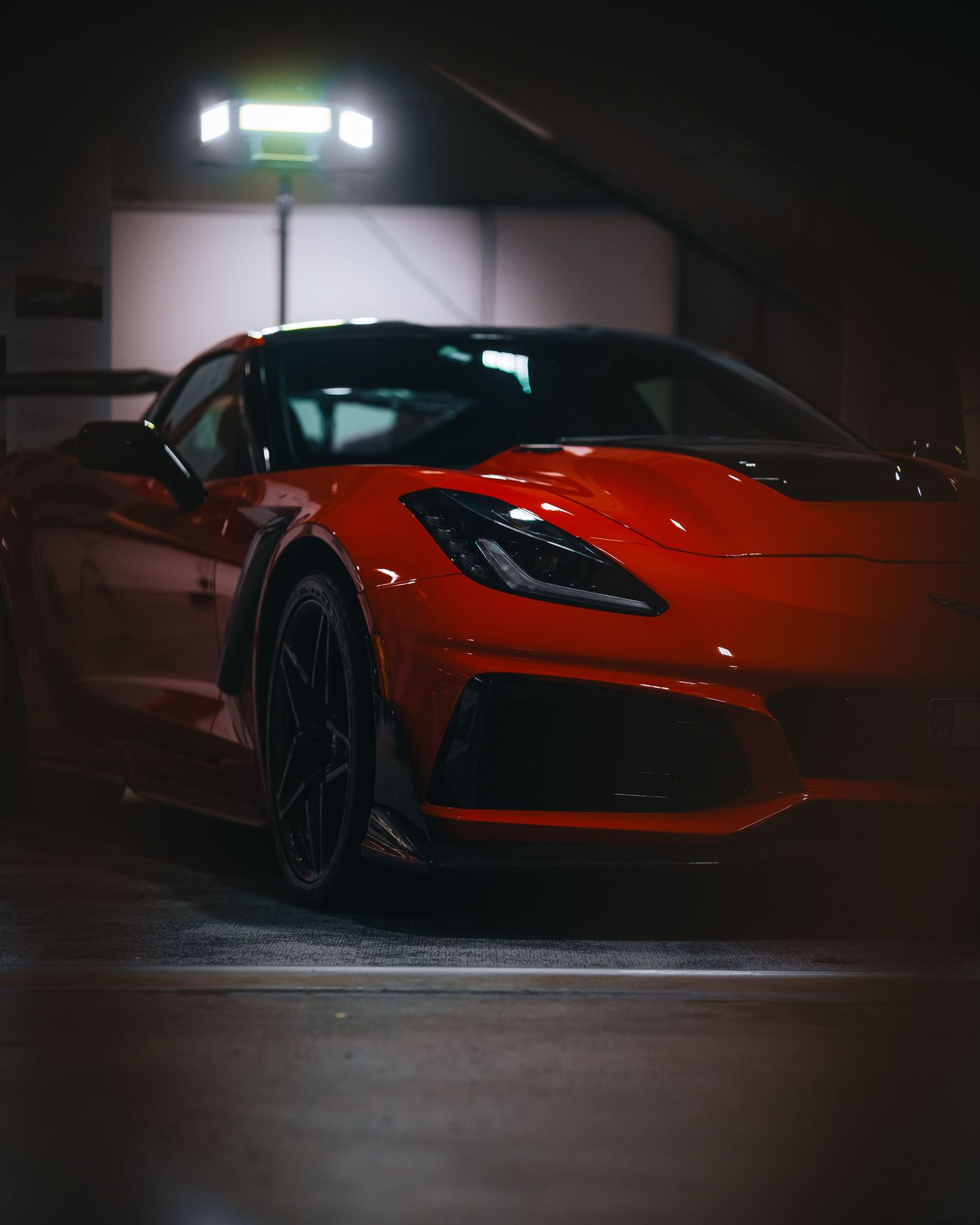 Side profile of a sleek red sports car in low light conditions.