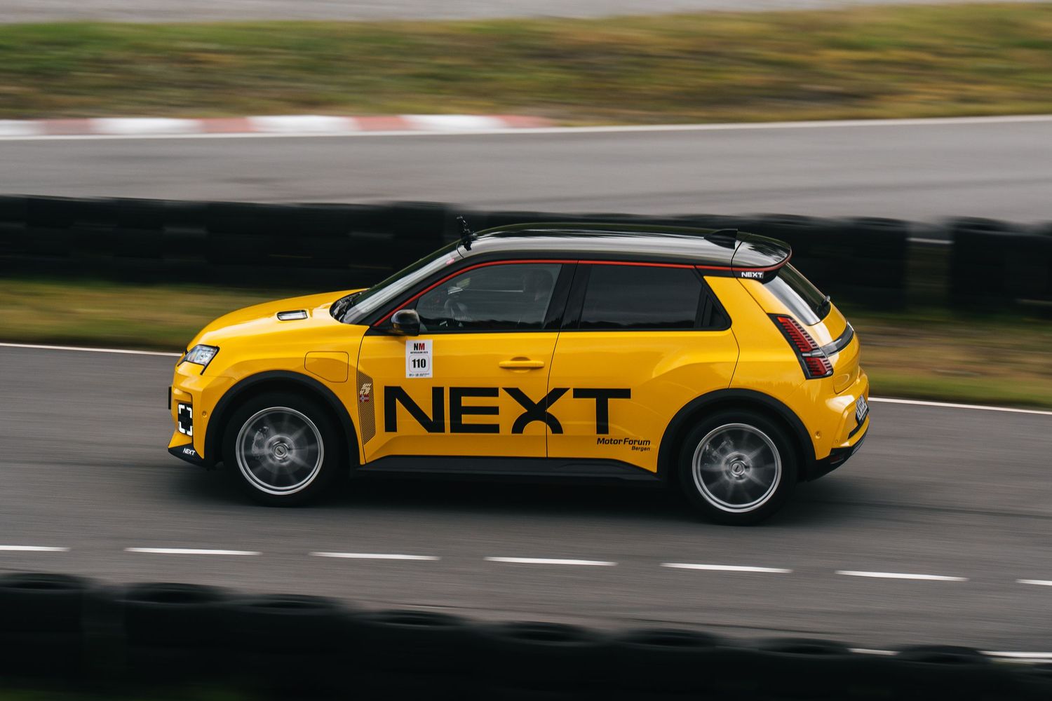 Yellow car in motion on a racetrack with blurred background showing speed and movement.