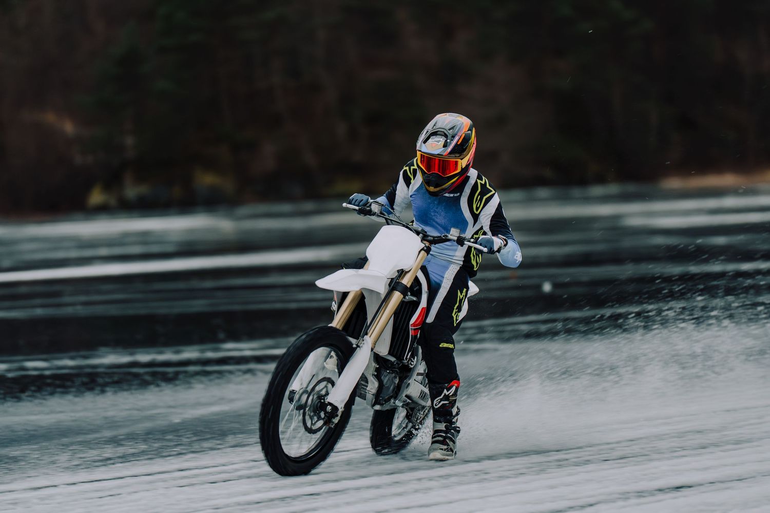 A motorcycle rider performs a thrilling ice racing maneuver on a frozen lake during winter competition.