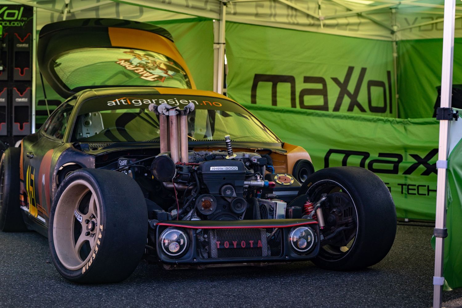 Custom black racing car with neon green accents and low-profile tires displayed at an auto show.