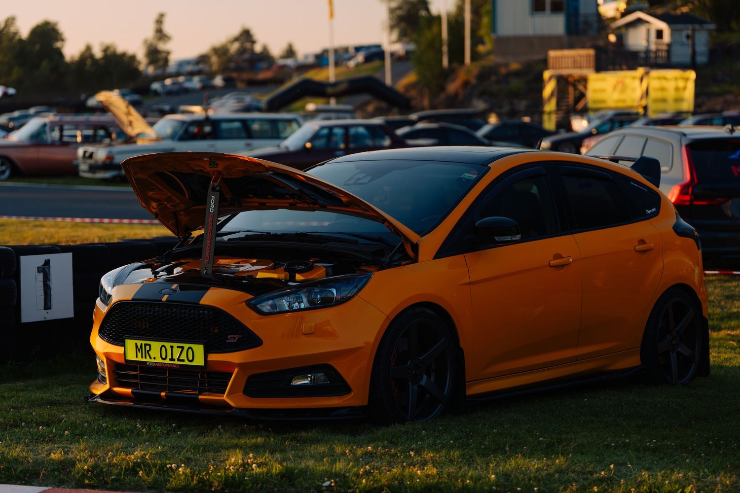 A series of sports cars lined up at sunset with dramatic lighting and shadows cast across their sleek bodies.
