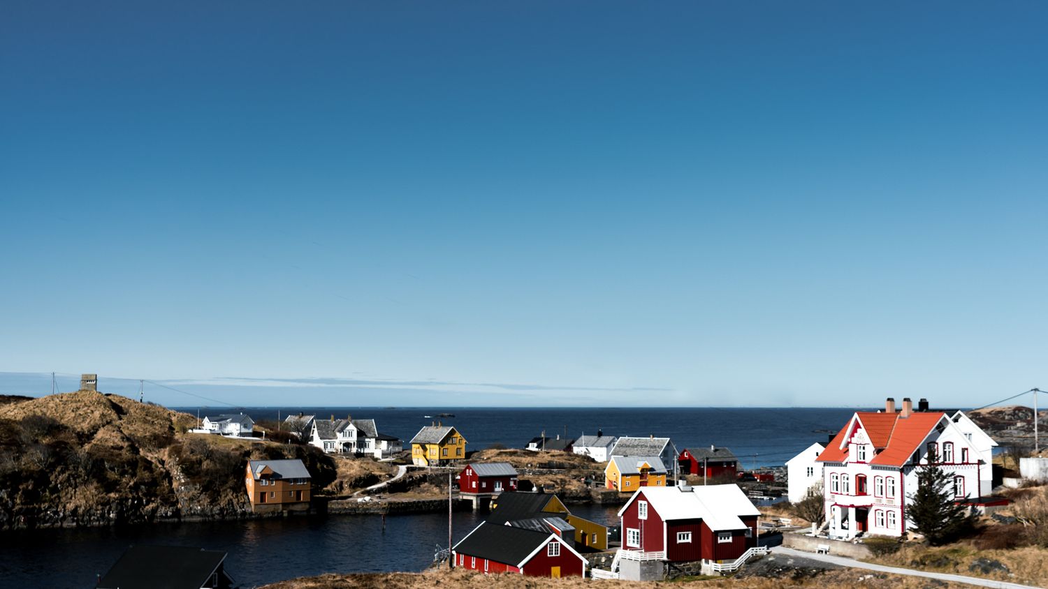 Colorful coastal houses and buildings nestled among rocky outcrops along a Norwegian fjord.
