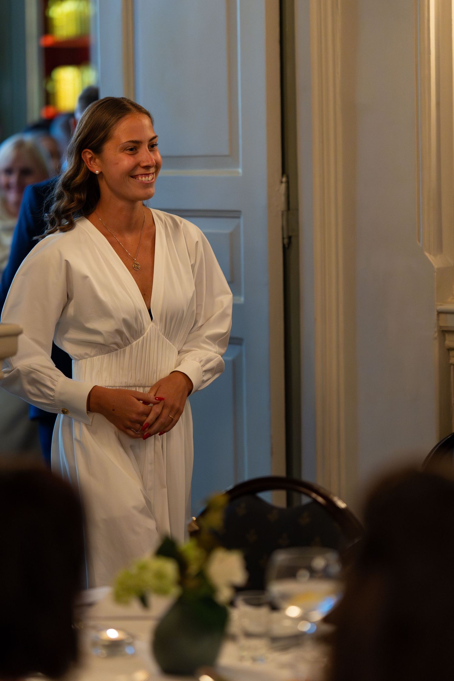Guest in white dress shares laughs during evening reception.
