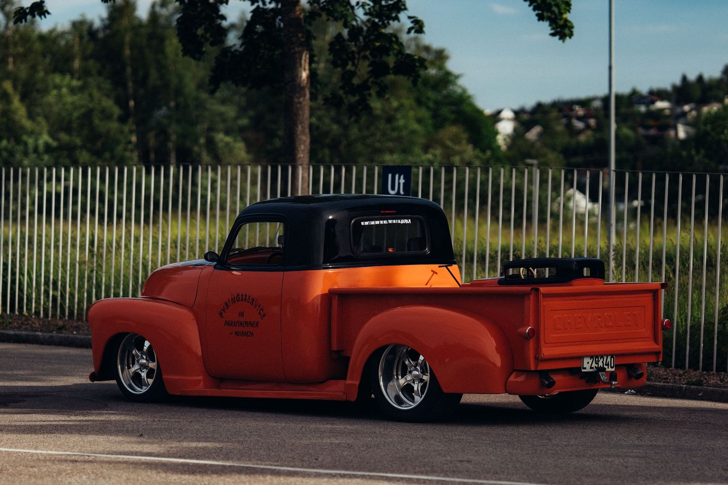 Custom orange and red classic cars showcased in a parking area.
