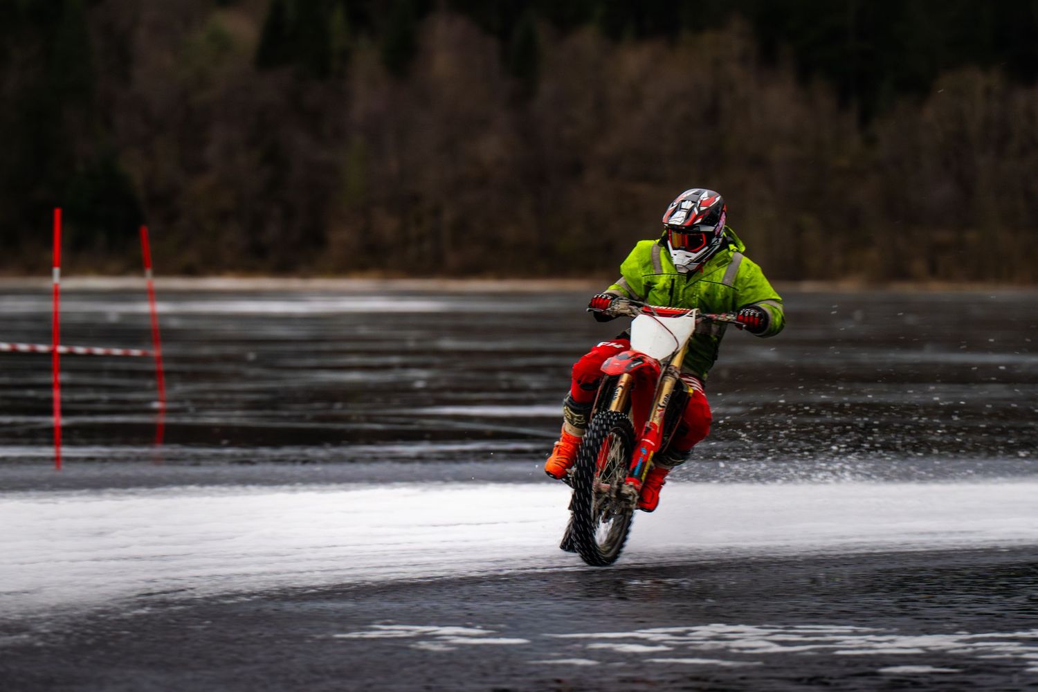 Motorcycles racing across a frozen lake surface with riders navigating between red slalom course markers.