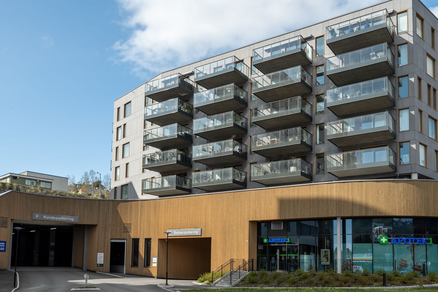 Modern apartment building with balconies and commercial space on ground floor.